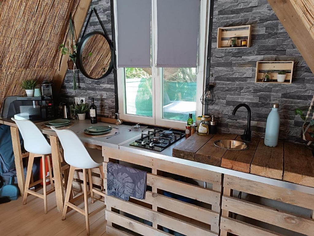 - une cuisine avec une cuisinière et un comptoir avec des tabourets dans l'établissement La cabane du phare du minou, à Plouzané