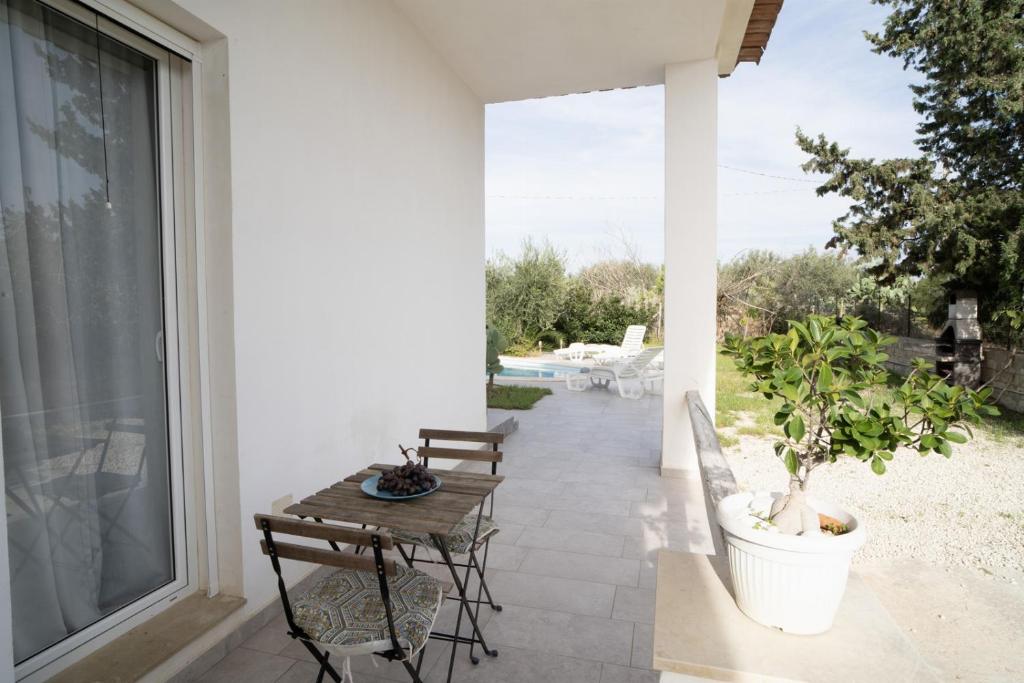 d'une terrasse avec une table et des chaises à côté d'une fenêtre. dans l'établissement Villa Malamuri, à Villaggio Azzurro