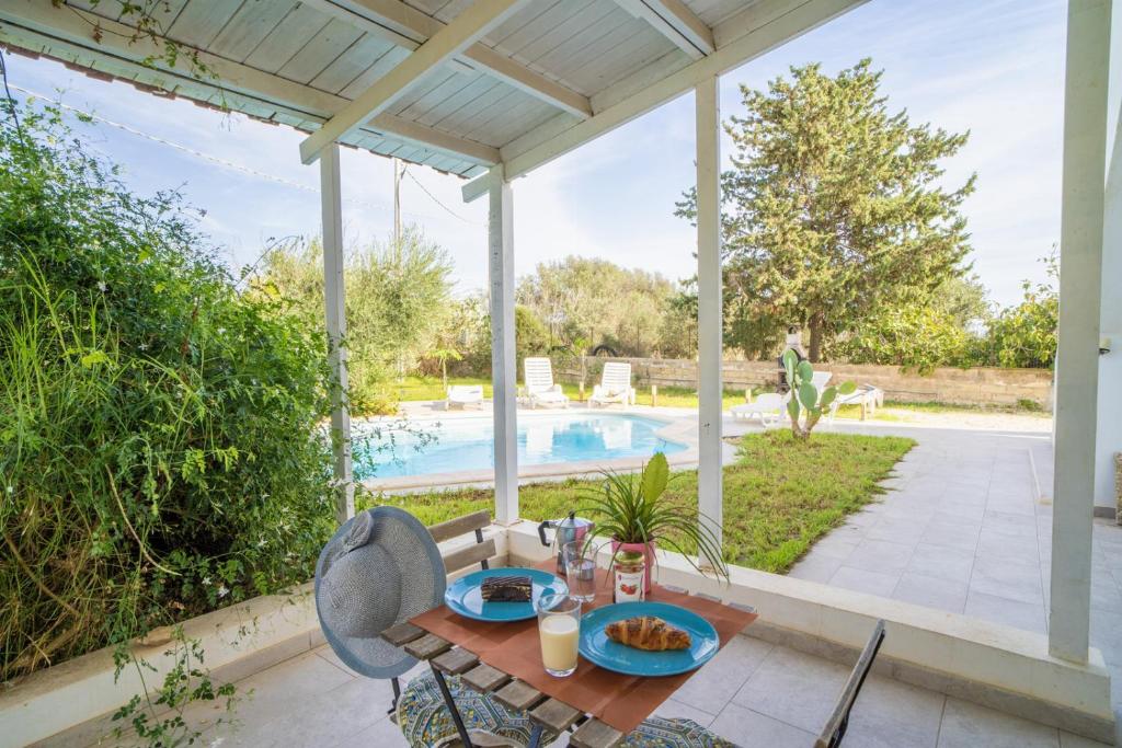 un patio avec une table et des chaises et une piscine dans l'établissement Villa Malamuri, à Villaggio Azzurro