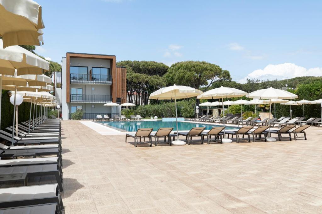 - une piscine avec des chaises et des parasols à côté d'un bâtiment dans l'établissement Hotel Gallia & Resort, à Lido di Jesolo