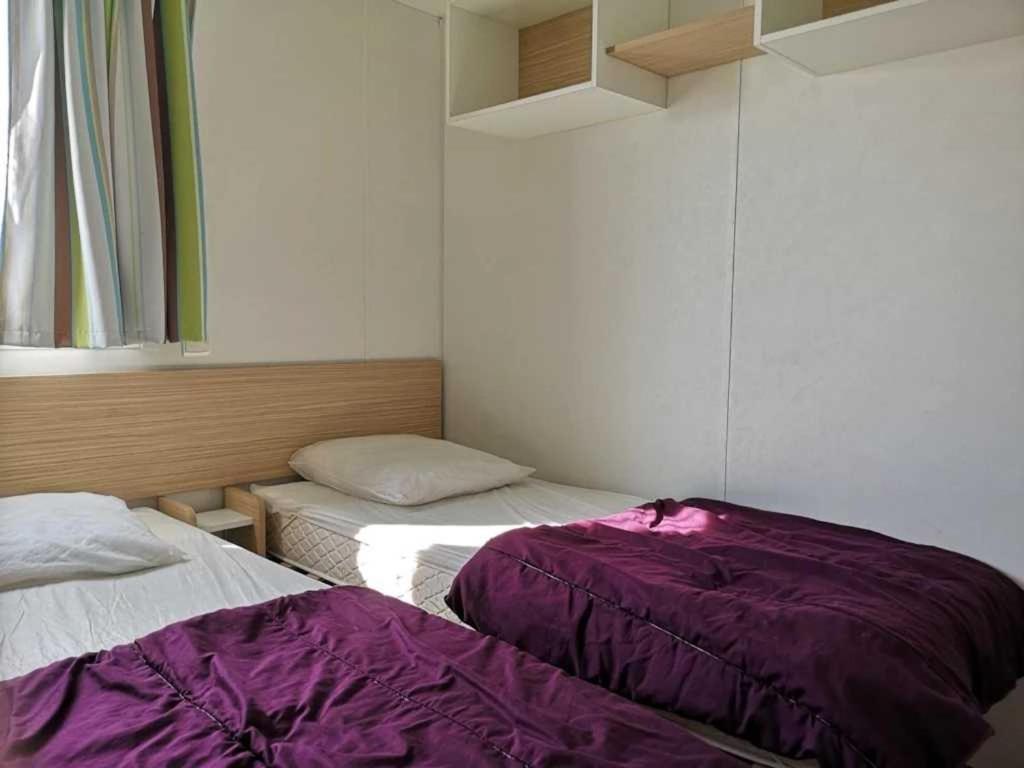 - 2 lits dans une chambre avec des draps violets dans l'établissement Camping 4 étoiles - Parc aquatique - efcia0, à Soullans