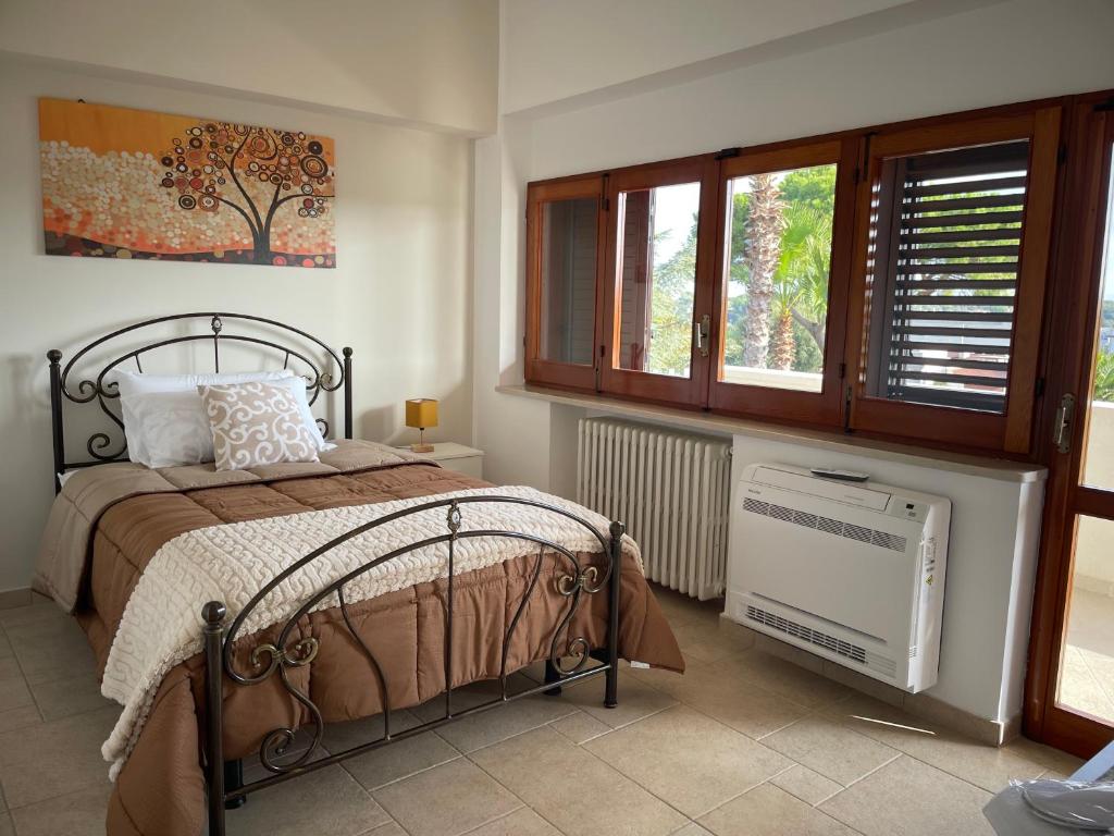 - une chambre avec un lit, un radiateur et des fenêtres dans l'établissement Antica Foggia Vetere villa con piscina, à Ceglie Messapica