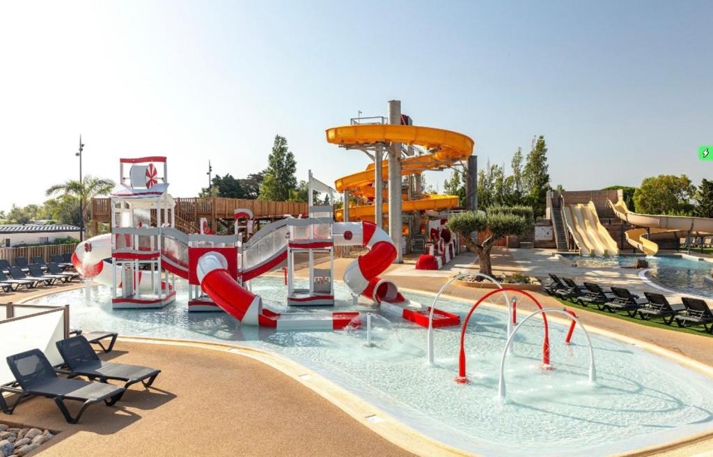 une piscine avec un parc aquatique avec un toboggan aquatique dans l'établissement LES DUNES - Les pieds dans l eau- TORREILLES PLAGE, à Torreilles