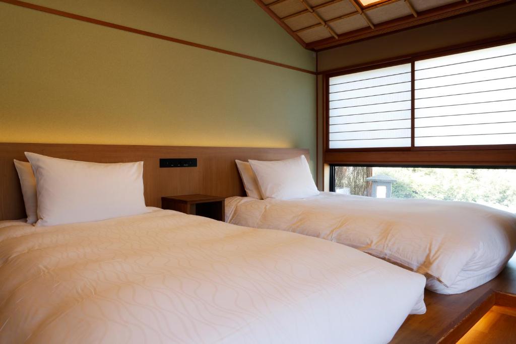 une chambre avec deux lits et une fenêtre dans l'établissement Kinosakinoyado Ryokufukaku, à Toyooka 37 autres photos