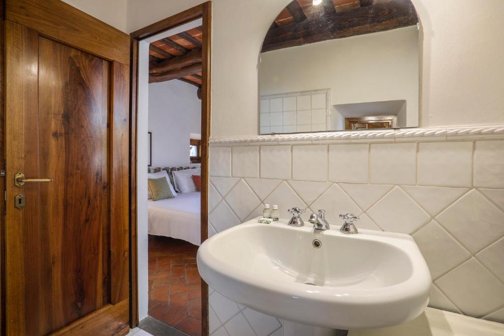 une salle de bain avec un lavabo, un miroir et un lit dans l'établissement Villa Laura, à Il Balzo