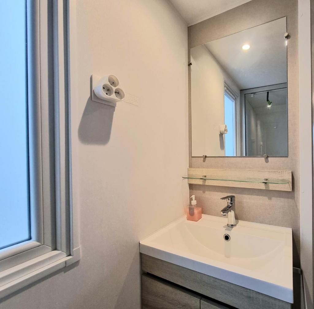 une salle de bain avec un lavabo et un miroir dans l'établissement Mobil home tout confort dans parc résidentiel de loisirs, à Saint-Hilaire-de-Riez