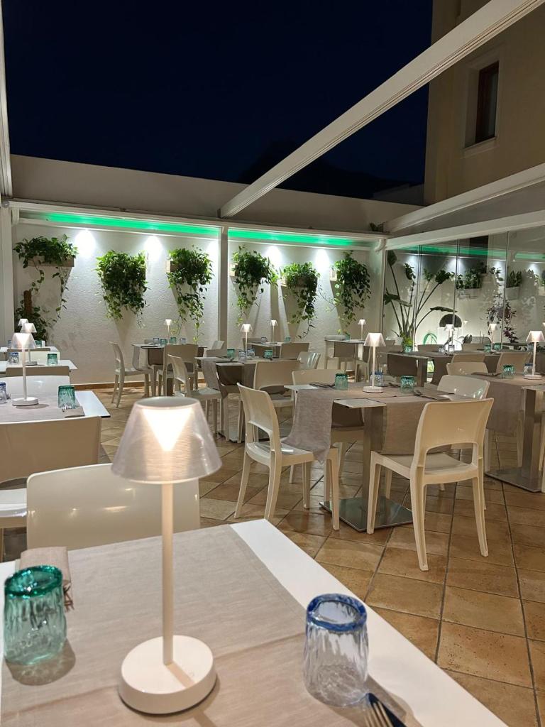 un restaurant avec des tables, des chaises et des plantes sur le mur dans l'établissement Hotel Trinacria, à San Vito Lo Capo 56 autres photos