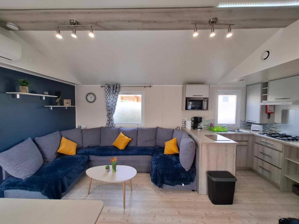 un salon avec un canapé bleu et une cuisine dans l'établissement Bungalow Cinéric, à Canet