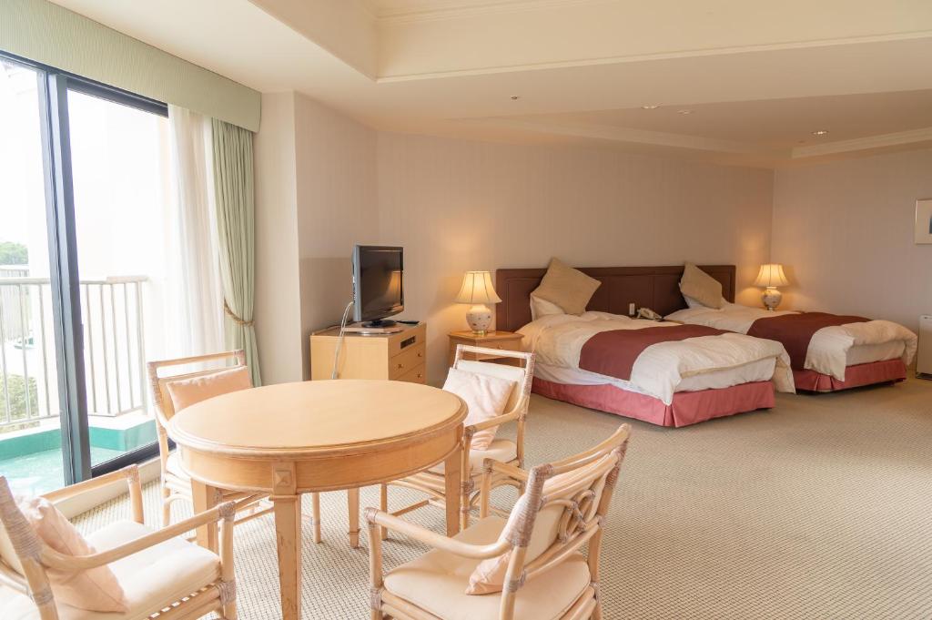 une chambre d'hôtel avec deux lits, une table et des chaises dans l'établissement Onahama Ocean Hotel & Golf Club, à Iwaki
