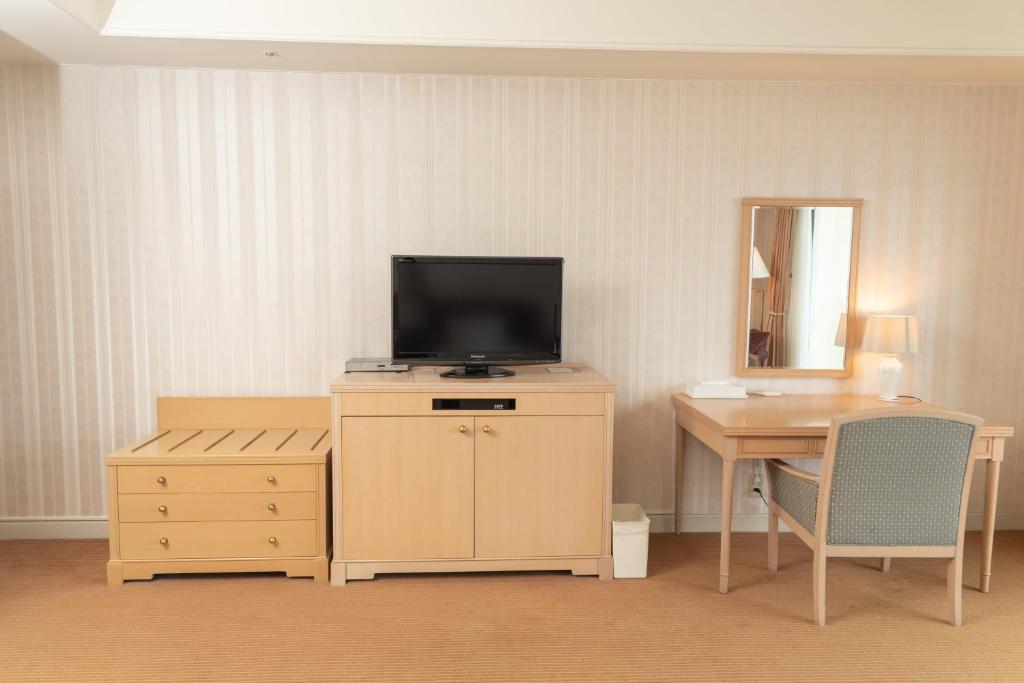 un salon avec une télévision sur une commode avec un bureau dans l'établissement Onahama Ocean Hotel & Golf Club, à Iwaki