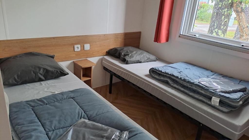 une petite chambre avec deux lits et une fenêtre dans l'établissement MH 480 2ch 2sdb 40m2 dans camping 4 étoiles avec parc aquatique, à Saint-Julien-en-Born
