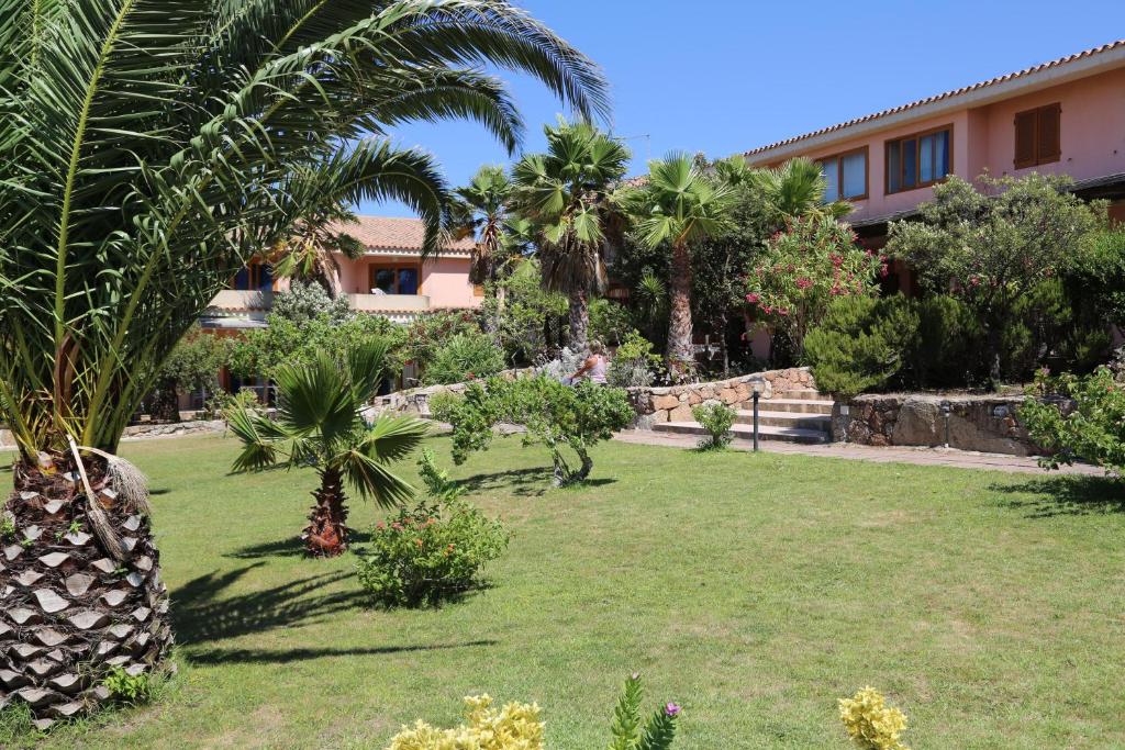 un jardin en face d'une maison avec des palmiers dans l'établissement Club Esse Residence Capo D'orso, à Palau
