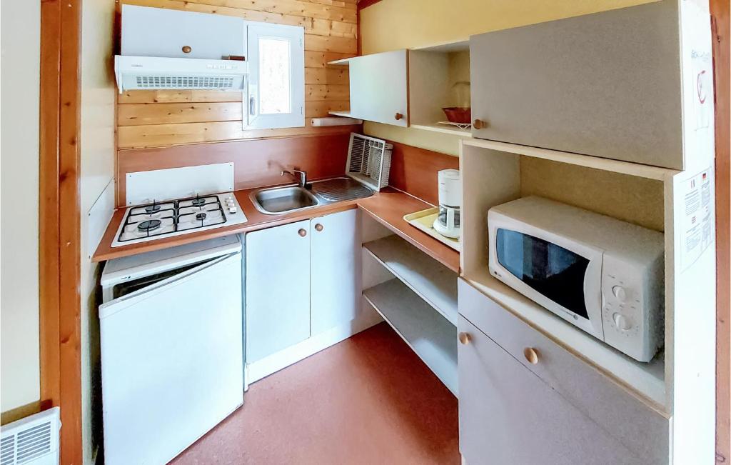 une petite cuisine avec des armoires blanches et un micro-ondes dans l'établissement Gorgeous StaCaravan In Chef-Boutonne, à Chef-Boutonne