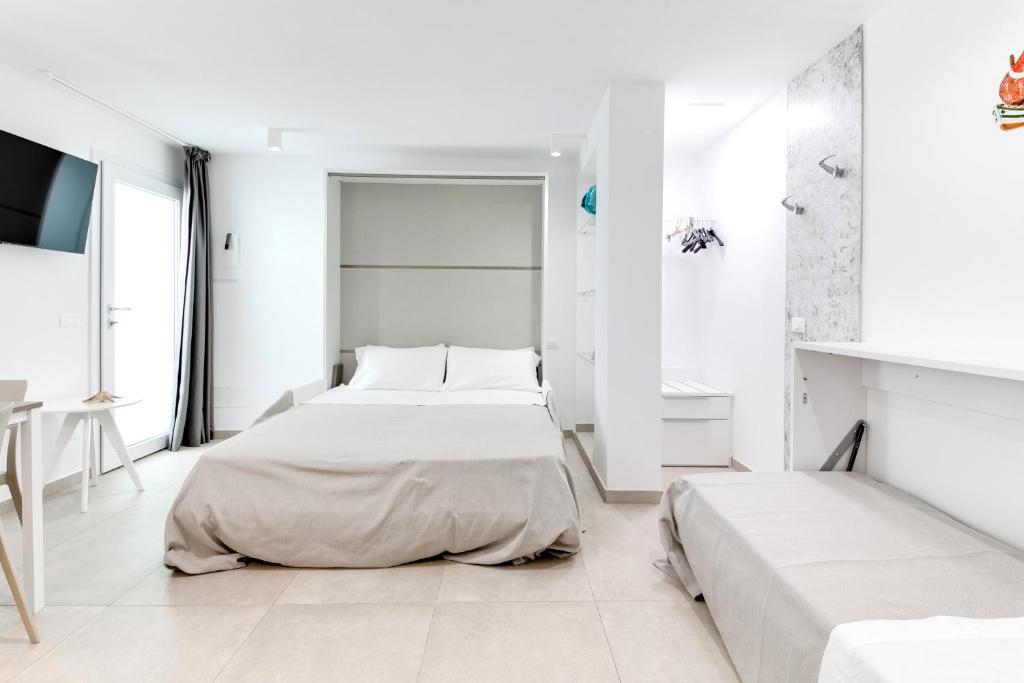 - une chambre blanche avec 2 lits et une table dans l'établissement Residence Diffuso Arcobaleno, à Gabicce Mare
