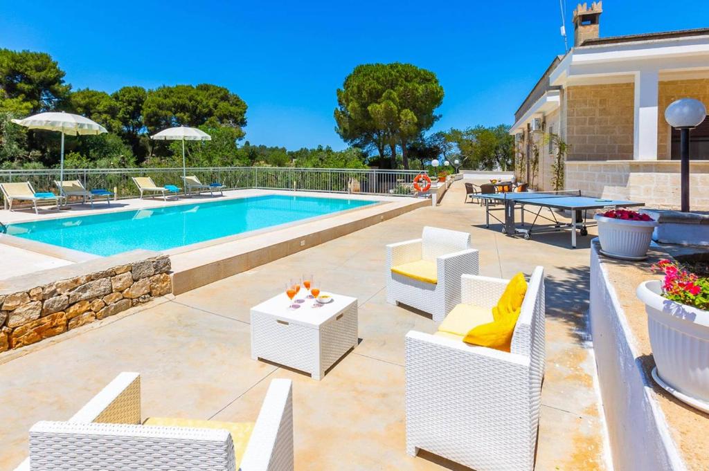 une terrasse avec des chaises blanches et une piscine dans l'établissement Villa Guglielmo by Villa Plus, à Carovigno 20 autres photos