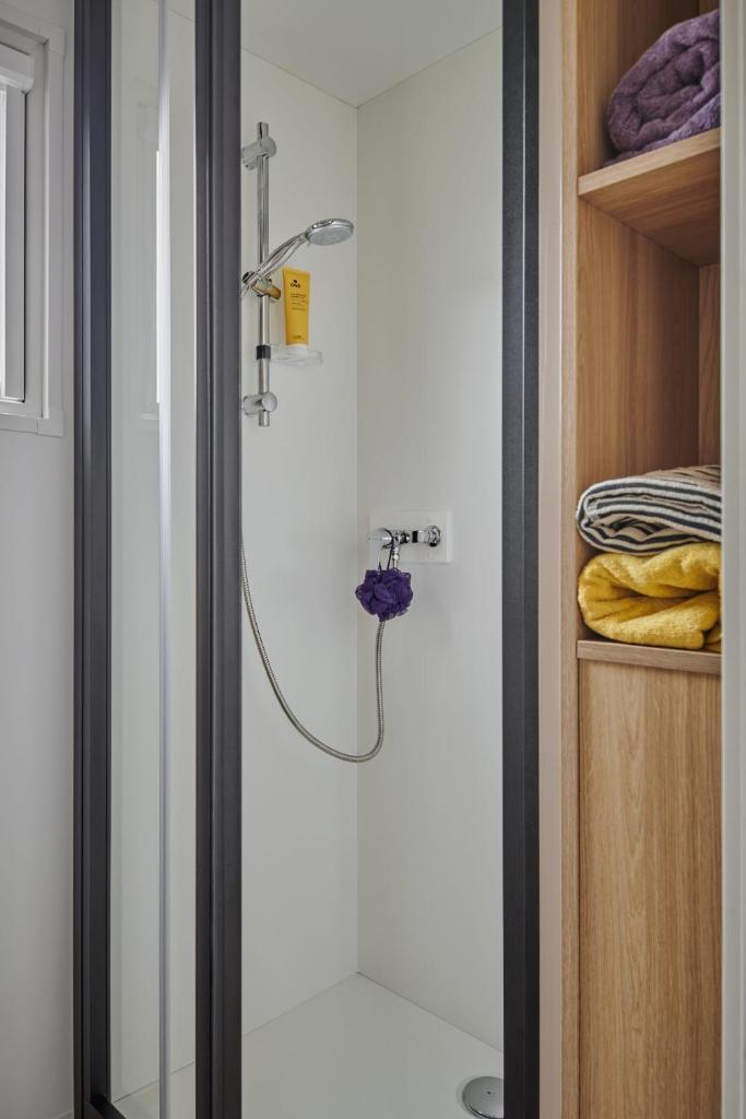 une douche dans une salle de bain avec une porte vitrée dans l'établissement Camping Club l'Air Marin, à Vias