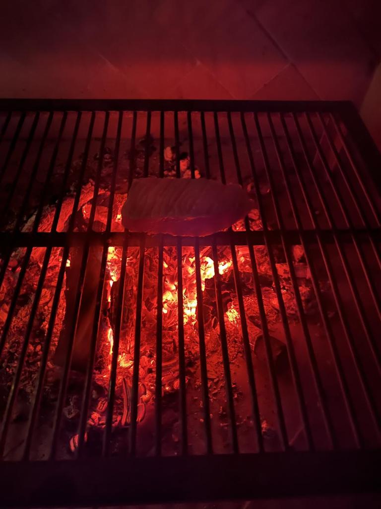 un morceau de viande cuisine sur un grill dans l'établissement Villa Acula, à Cannigione