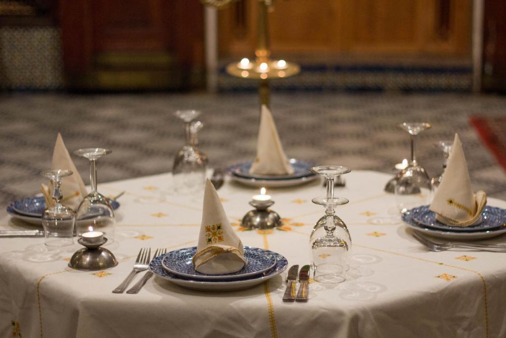 - une table avec des assiettes bleues et blanches et des verres à vin dans l'établissement Riad Ibn Khaldoun, à Fès