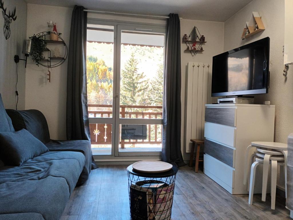 un salon avec un canapé et une grande fenêtre dans l'établissement Studio 2 alpes, proche lac buissonnière, ménage inclus, balcon, parking, à Les Deux Alpes