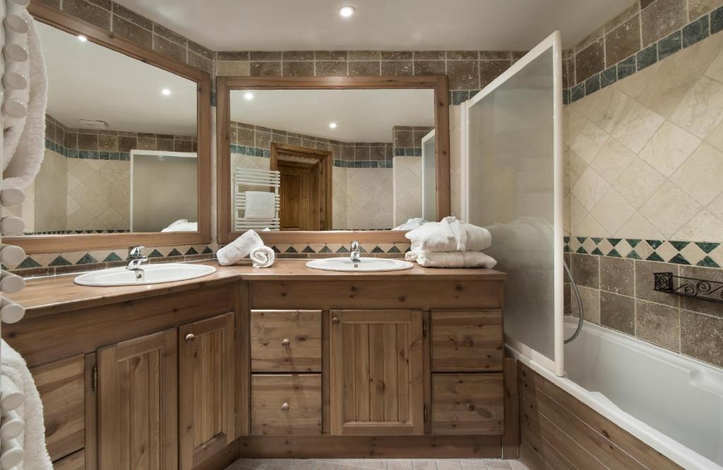 une salle de bain avec deux lavabos et un grand miroir dans l'établissement Ancolies Val Thorens, à Val Thorens