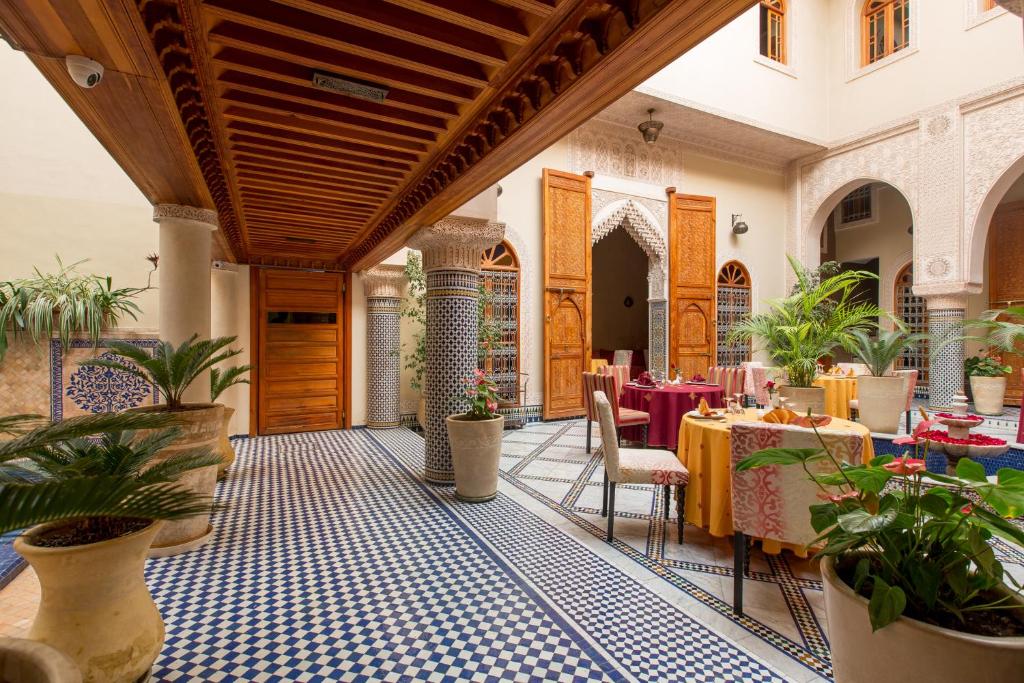 un restaurant avec des tables, des chaises et des plantes dans l'établissement Riad Andalib, à Fès