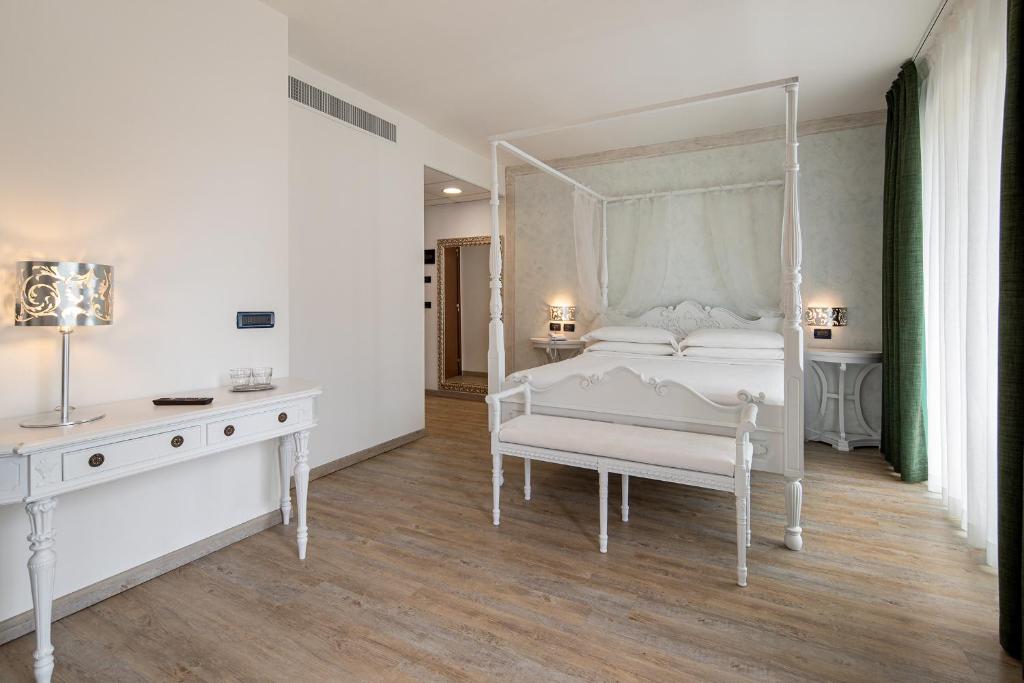 une chambre blanche avec un lit à baldaquin blanc et un bureau dans l'établissement Fantinello Hotel, à Caorle