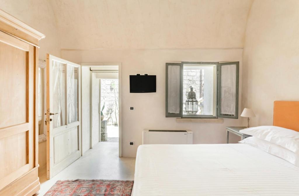 - une chambre avec un lit blanc et une télévision murale dans l'établissement Wp RELAIS LOCANDA FIORE DI ZAGARA, à Diso