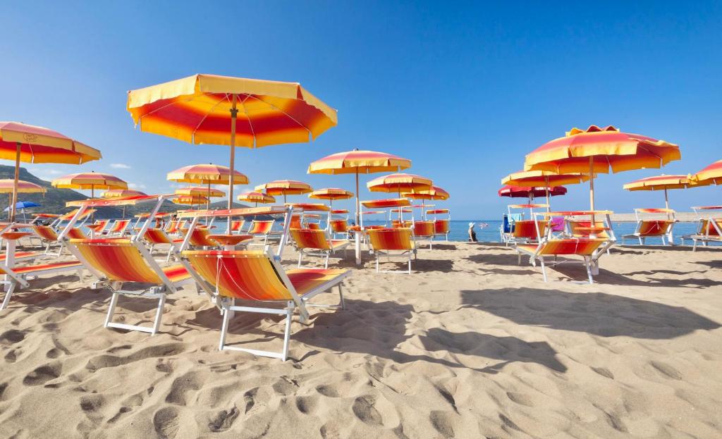 - un bouquet de chaises et de parasols sur une plage dans l'établissement ISA-Residence with private beach in Bosa Marina just 100 meters from the sea, à Bosa Marina