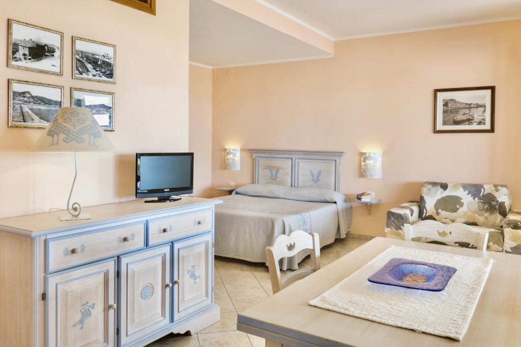 une chambre avec un lit, une télévision et un canapé dans l'établissement ISA-Residence with private beach in Bosa Marina just 100 meters from the sea, à Bosa Marina