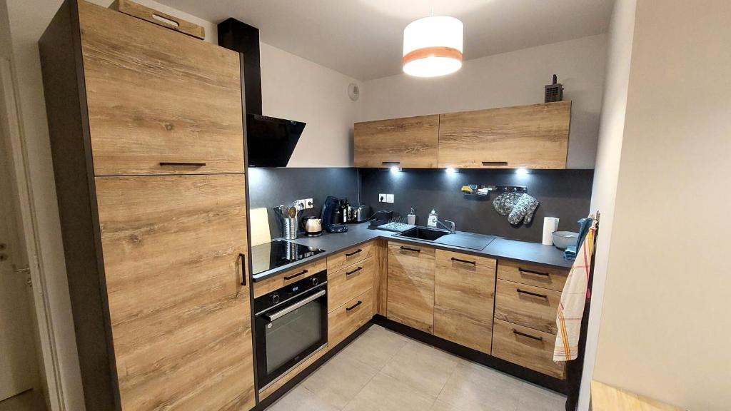 une cuisine avec des armoires en bois et un four à plaques de cuisson dans l'établissement Large new T2 with terrace le dahu perché, au Monêtier-les-Bains
