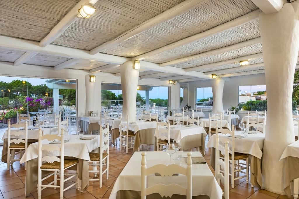 une salle de banquet avec des tables et des chaises blanches dans l'établissement Grand Hotel In Porto Cervo, à Porto Cervo