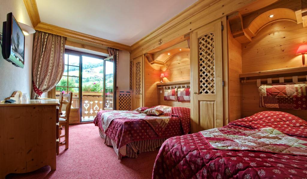 une chambre d'hôtel avec deux lits et une fenêtre dans l'établissement Hotel les Sapins, à La Clusaz