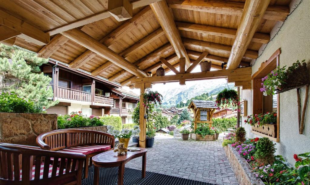 un patio extérieur avec une pergola en bois dans l'établissement Hotel les Sapins, à La Clusaz