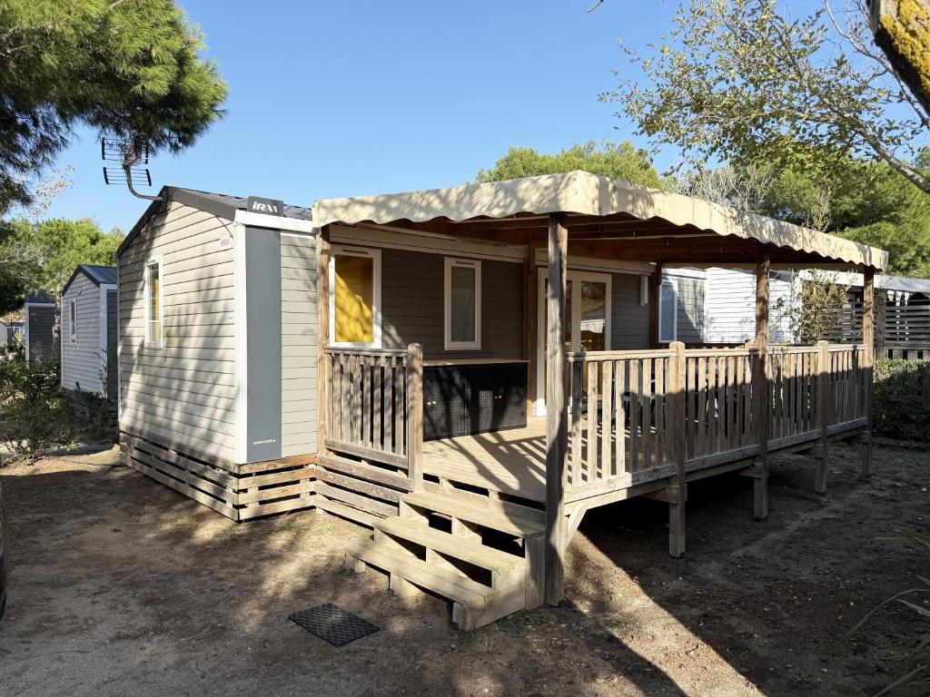 une petite maison avec un porche et une terrasse dans l'établissement Mobil-home - Camping Le Marisol - Torreilles-plage, à Torreilles