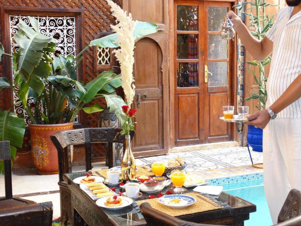 Une femme debout à côté d'une table avec de la nourriture et des boissons dans l'établissement Riad Dar El Bacha, à Marrakech
