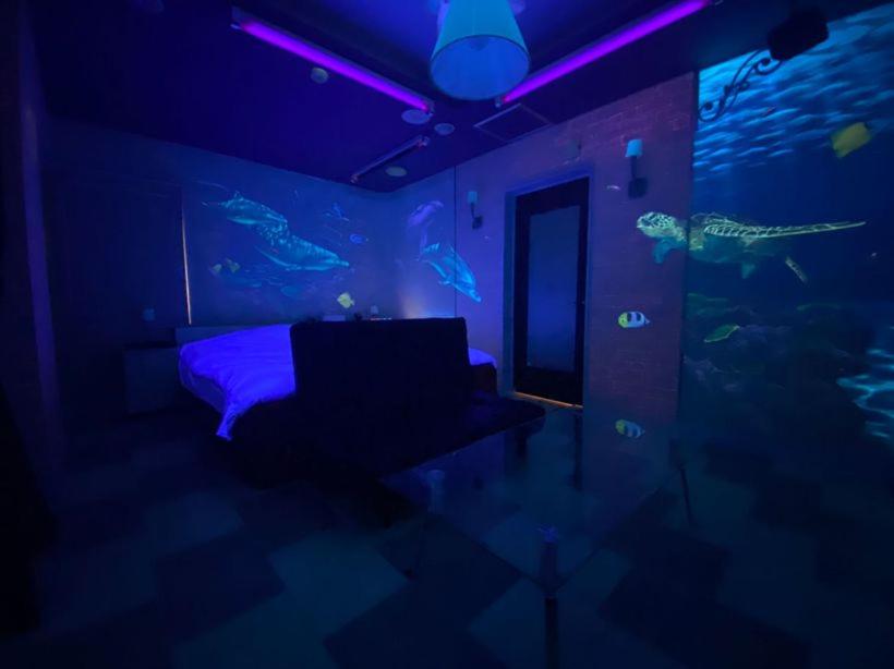 Cette chambre comprend un lit et un aquarium avec des poissons. dans l'établissement Hotel LIBERTY一宮店, à Fuefuki