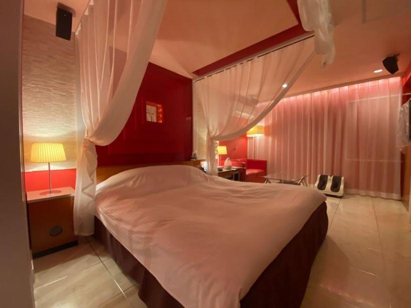 une chambre avec un grand lit aux murs rouges dans l'établissement Hotel LIBERTY一宮店, à Fuefuki
