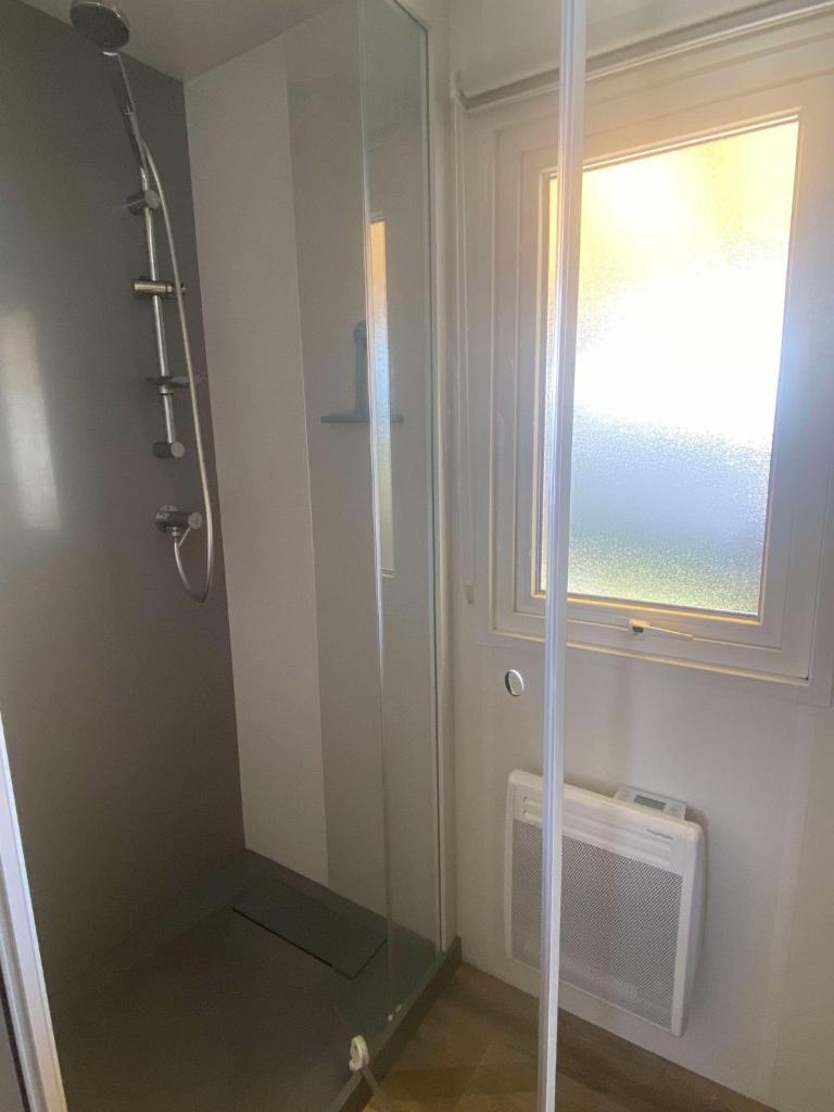 La salle de bains est pourvue d'une douche en verre et d'une fenêtre. dans l'établissement Mobil home, à Parentis-en-Born 10 autres photos