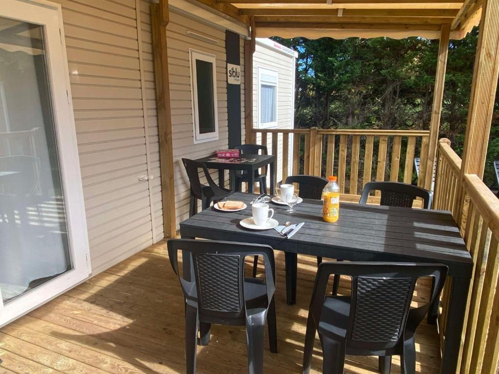 - une table et des chaises noires sur une terrasse couverte dans l'établissement Mobil home, à Parentis-en-Born