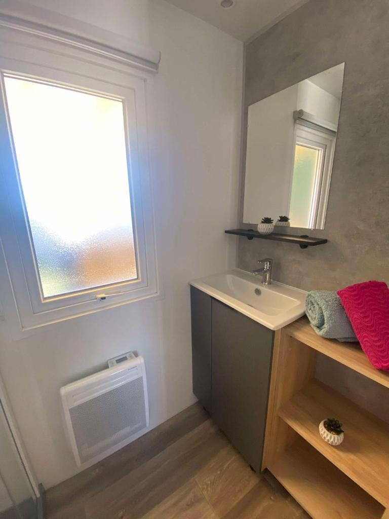 une salle de bain avec un lavabo et une fenêtre dans l'établissement Mobil home, à Parentis-en-Born