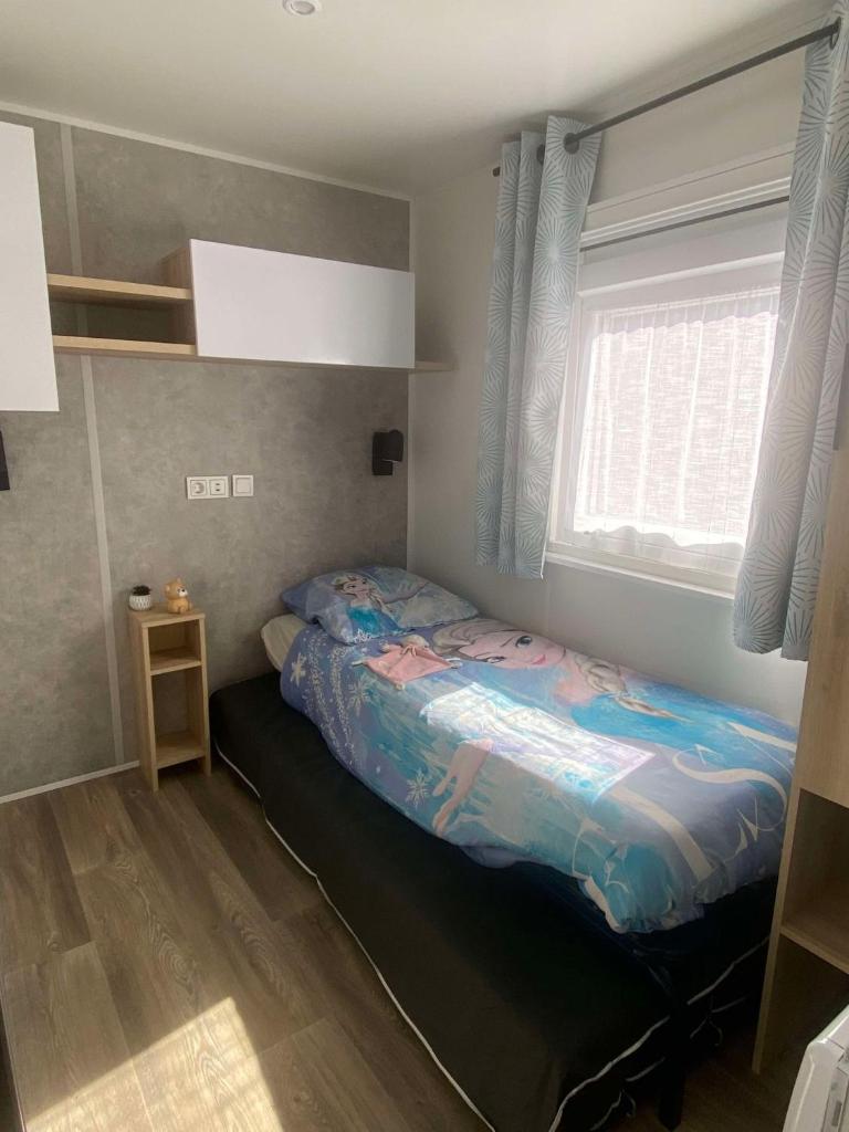 une chambre avec un lit dans une pièce avec une fenêtre dans l'établissement Mobil home, à Parentis-en-Born