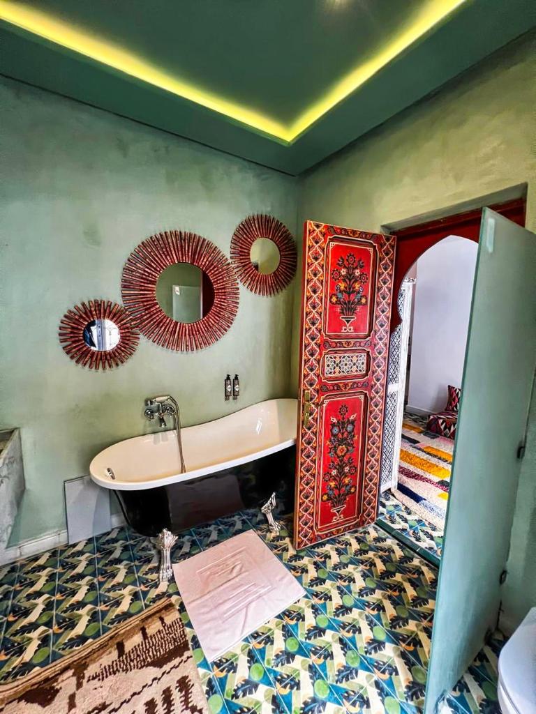 La salle de bains est pourvue d'une baignoire et de miroirs sur le mur. dans l'établissement Riad dar darcom, à Marrakech