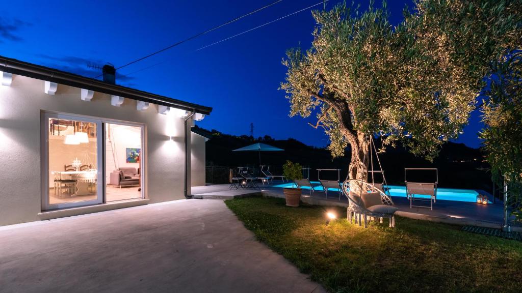 une maison avec un arbre et une piscine la nuit dans l'établissement Dimora Campo delle Mura - Charming House, à Acquaviva Picena
