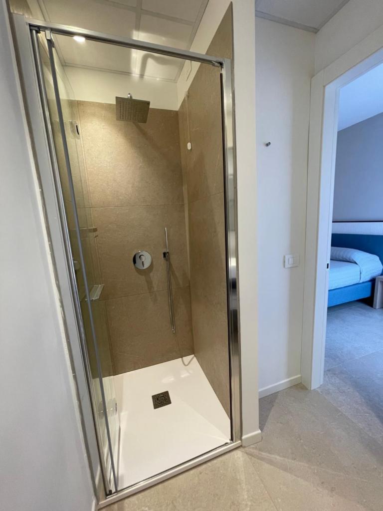 une douche avec une porte vitrée dans une salle de bain dans l'établissement Petit Hotel, à Caorle
