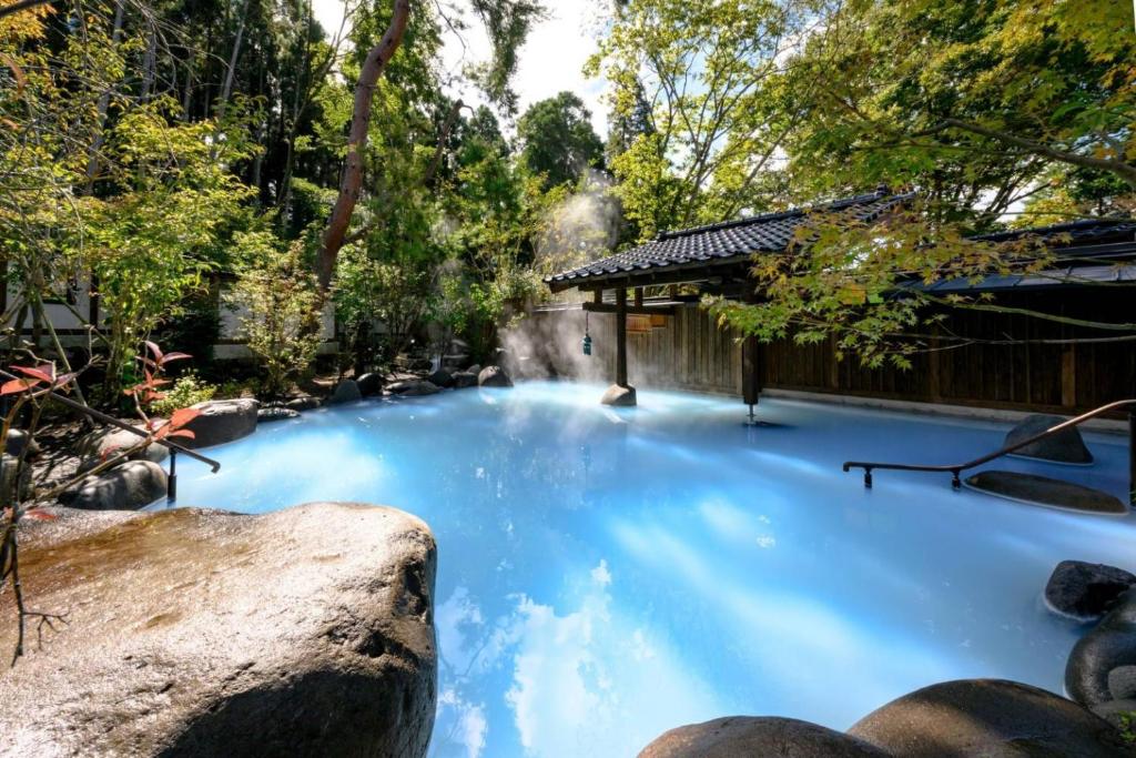 une grande piscine d'eau bleue dans un jardin dans l'établissement Taisho Yufu no Hana, à Yufu