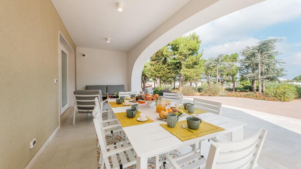 une salle à manger avec une table et des chaises blanches dans l'établissement VILLA BELLINA 6, Emma Villas, à Ostuni