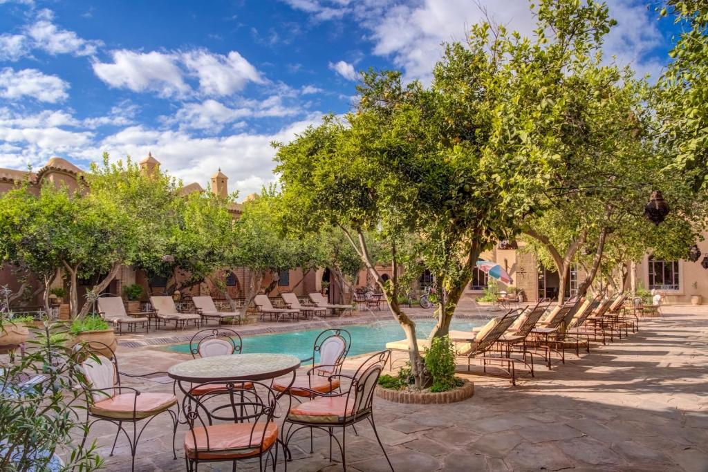 un patio avec tables et chaises à côté d'une piscine dans l'établissement Riad Jnane Ines, à Taroudant