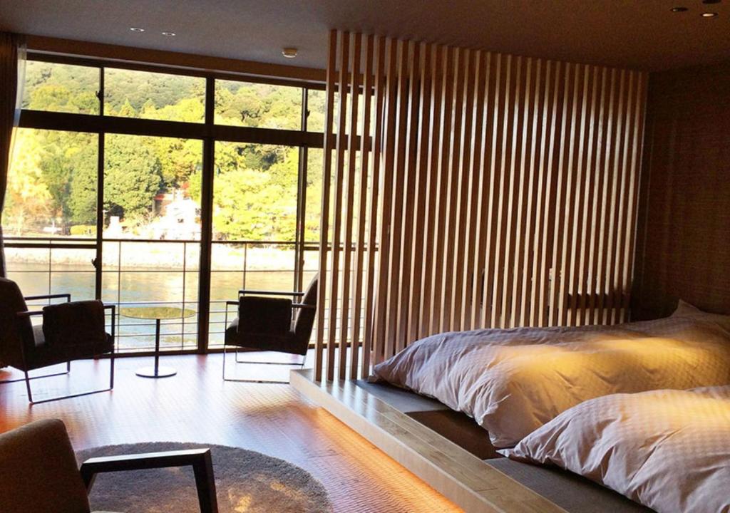 une chambre avec un lit et une grande fenêtre dans l'établissement Hanayashiki Ukifune-en, à Uji