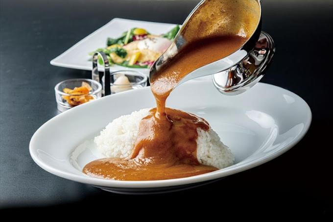 Une cuillère verse de la sauce sur une assiette de nourriture dans l'établissement Hotel Stay Forest (Love Hotel), à Tsuchiura