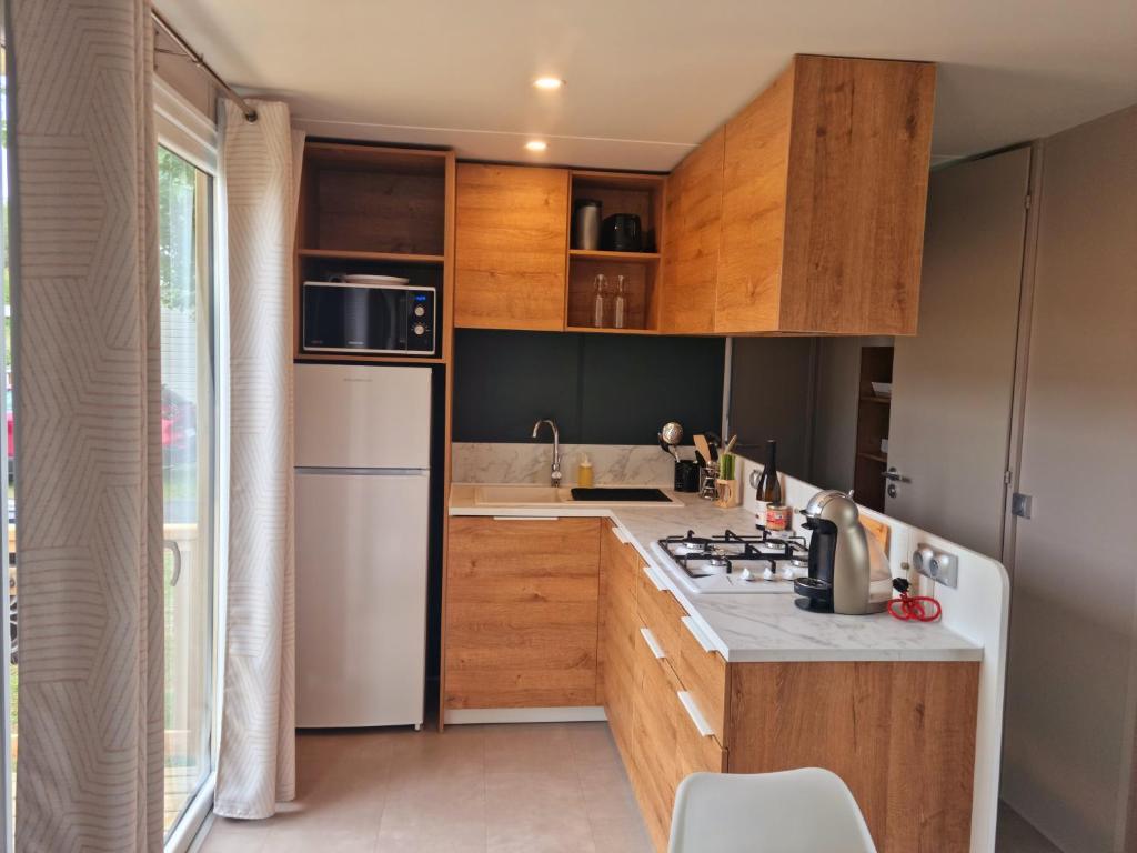 une cuisine avec des armoires en bois et un réfrigérateur blanc dans l'établissement MOBILHOME 8p 3 CH 2 SDB SAINT JEAN DE MONTS, à Saint-Jean-de-Monts